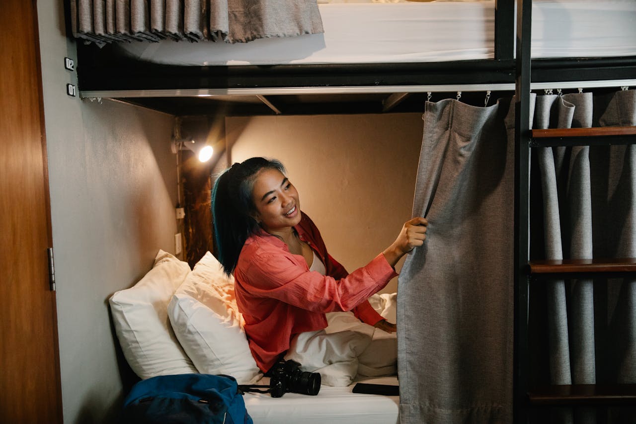 Home Young woman enjoys comfort in a cozy hostel bunk bed, surrounded by soft lighting.